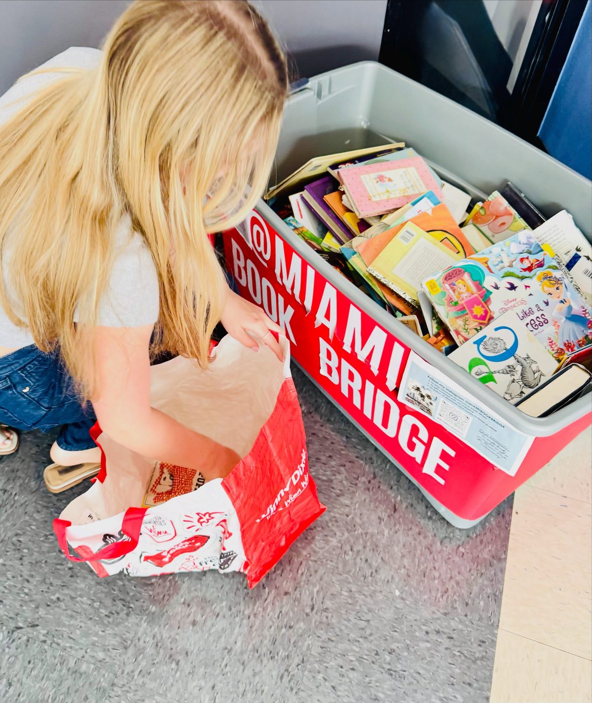 Unloading donated children's books from the red Miami Book Bridge donation bin