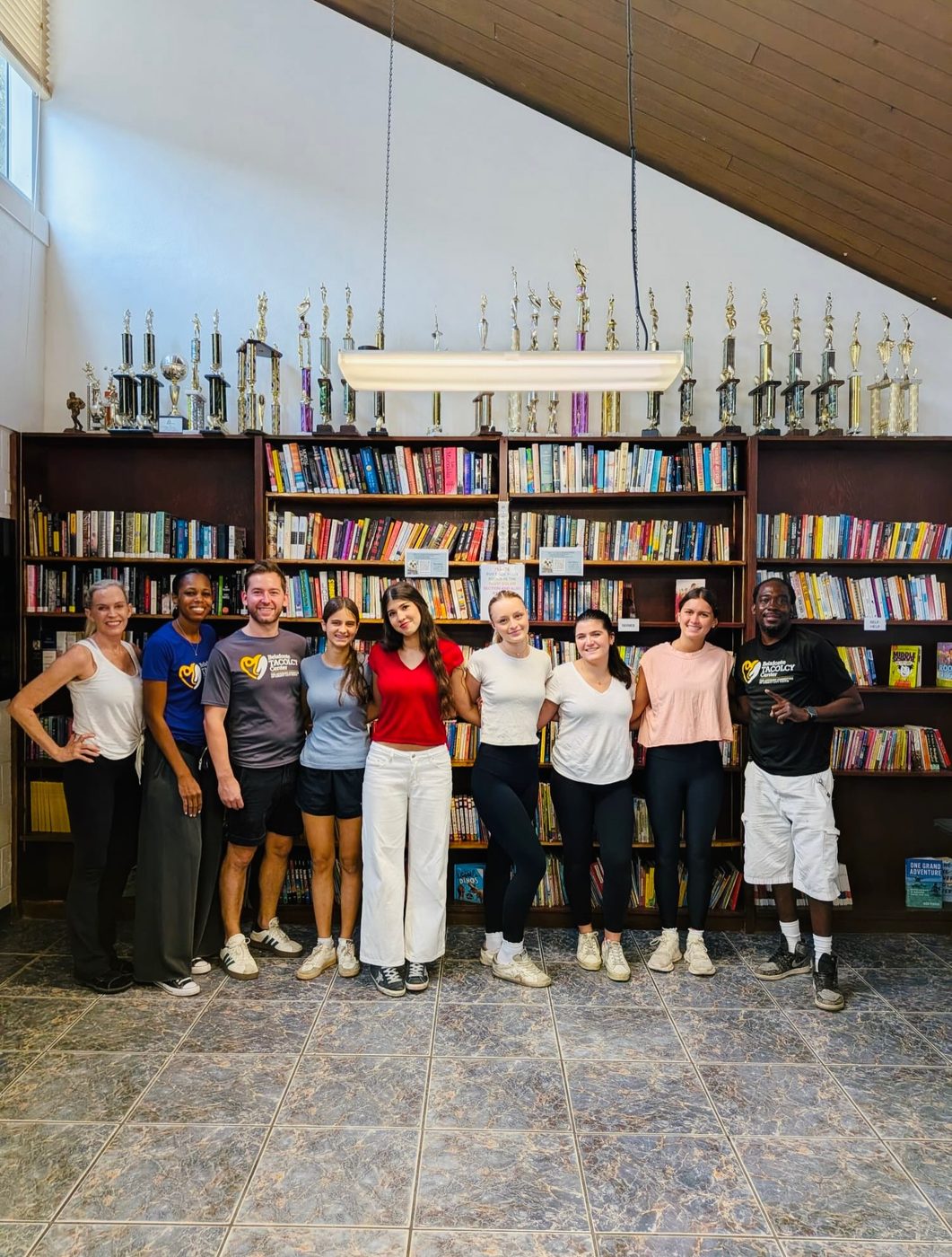 Volunteers and TACOLCY Center staff standing in front of the newly stocked library shelves